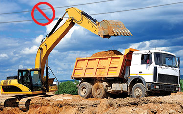 Excavator loading dumper truck with unsafe wires above