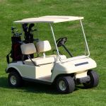 Golf cart with golf clubs in back on grass