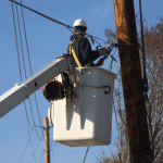 Utility worker in bucket working near power lines