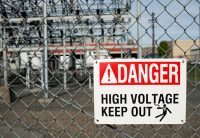 Danger high voltage keep out sign on fence in front of substation
