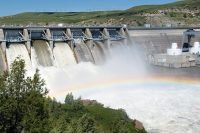Water falling from hydro dam creating rainbow over larger body of water