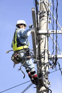 Lineman attached to pole working on equipment